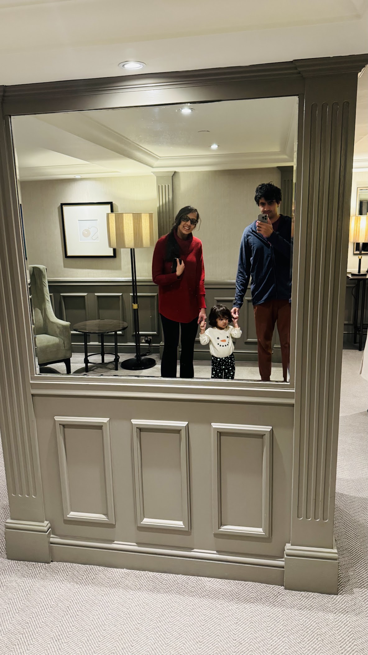 Family reflected in The Churchill's lobby mirror, classic wainscoting and sage furnishings