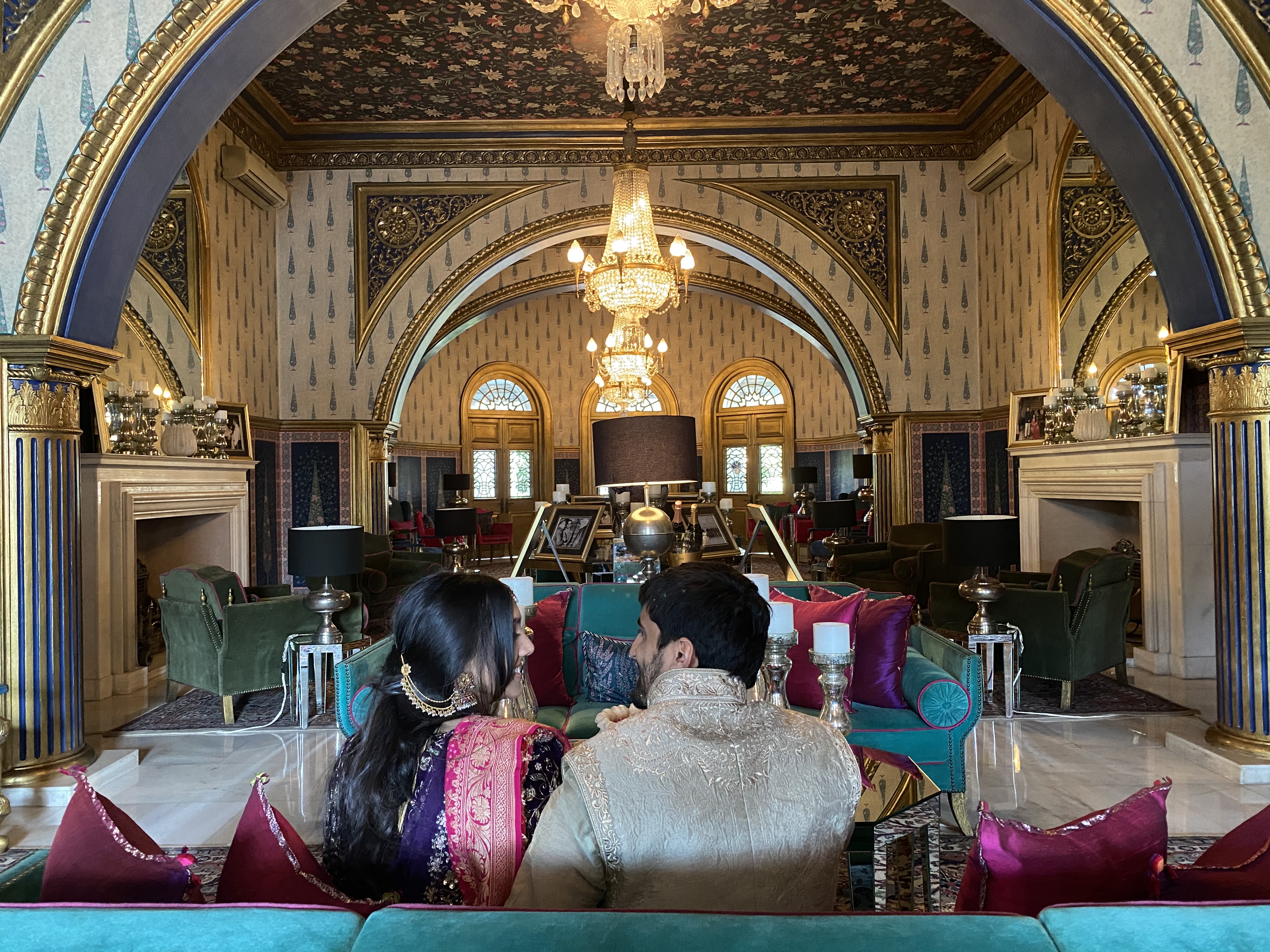 The palace lounge at Rajmahal with gilded arches, crystal chandeliers, and ornate wallpaper